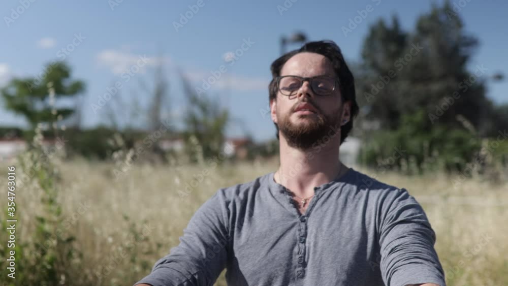 Beautiful man is meditating and enjoying the nature taking long breathes, then smiles. Concept of outdoor relaxation. Portrait shot Beautiful man is meditating and enjoying the nature taking long breathes, then smiles. Concept of outdoor relaxation. Portrait shot