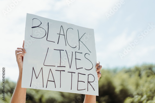 No rasicm.Crowd of protesters people on street.black woman raised hands showing sign black lives matter for revolution protest.Justice in USA.