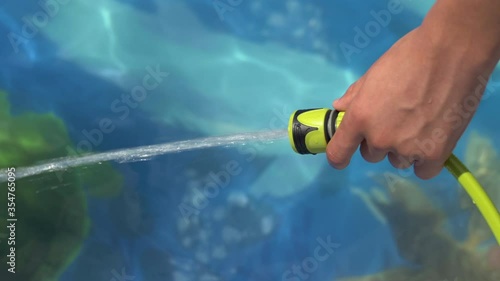 teenager hand filling Inflatable pool with water from hose in garden in england uk
