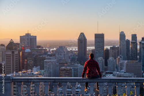 Montreal, Canada - may 2020 : back view of a young man wearing a lumberjack shirt, admiring the sunrise from the Kondiaronk belvedere  