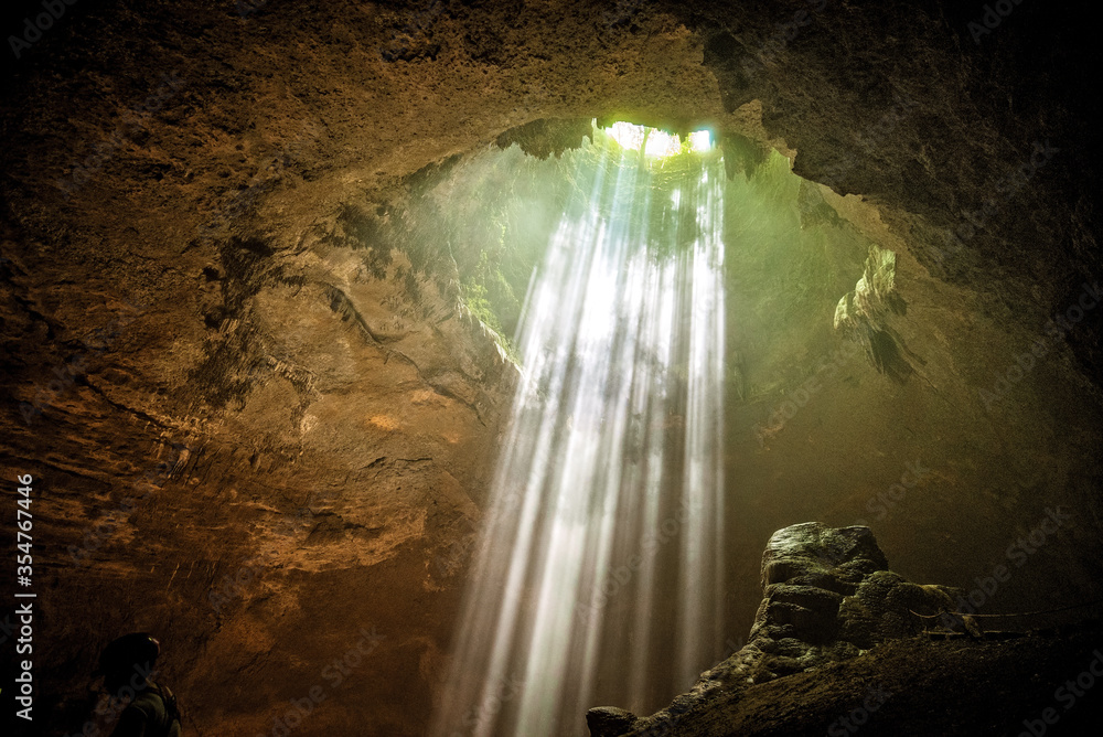 rays of light shine through at Jomblang cave near Yogyakarta, Indonesia - obrazy, fototapety, plakaty 