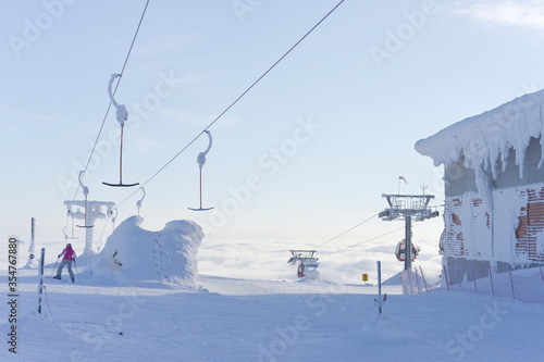 At the top of ski lifts as they rise above the clouds, covered in snow, only 1 skier
