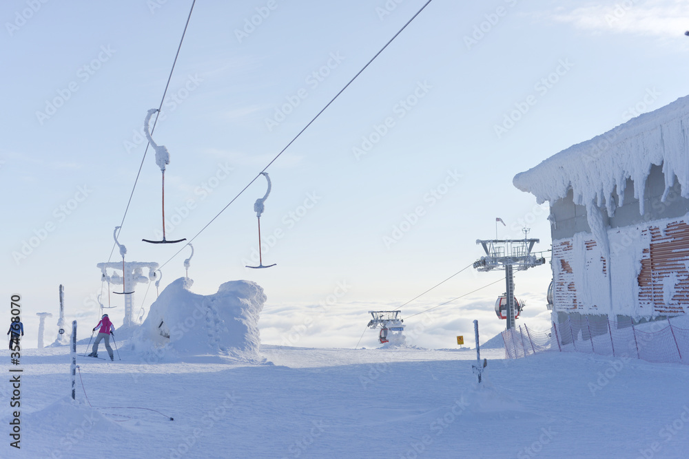 At the top of ski lifts as they rise above the clouds, covered in snow. At the top of ski lifts as they rise above the clouds, covered in snow.