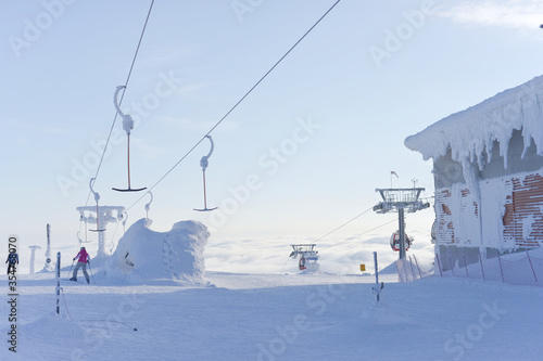 At the top of ski lifts as they rise above the clouds, covered in snow.