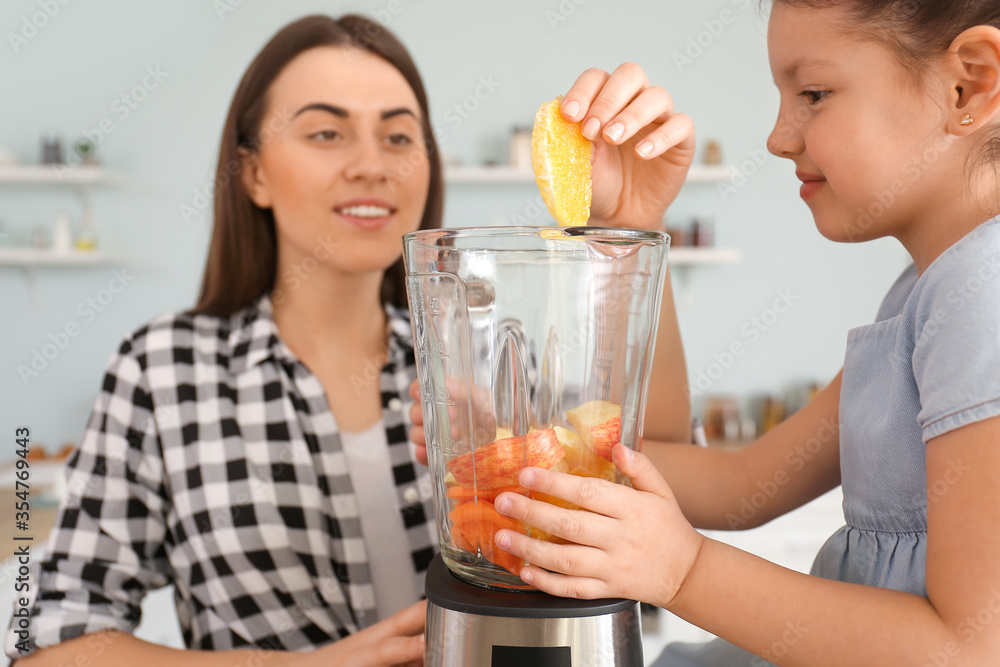 Mother and little daughter making healthy smoothie in kitchen Mother and little daughter making healthy smoothie in kitchen
