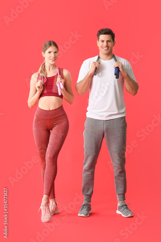 Sporty young couple on color background