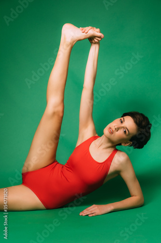 young woman doing stretching and gymnastic exercises on green chromakey