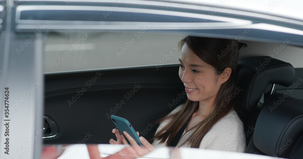 Woman use mobile phone and sits inside car