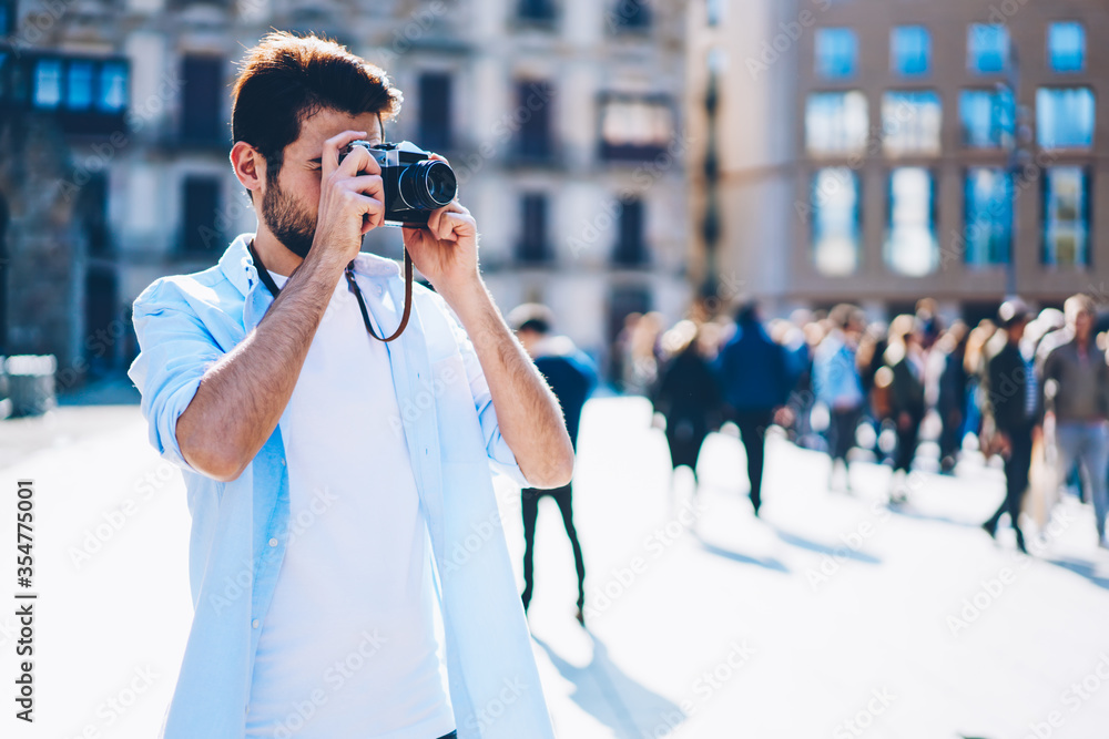 Hipster guy focusing to take pictures standing in urban setting Hipster guy focusing to take pictures standing in urban setting