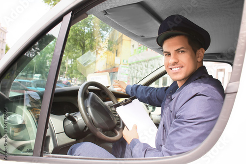 Handsome young postman in car