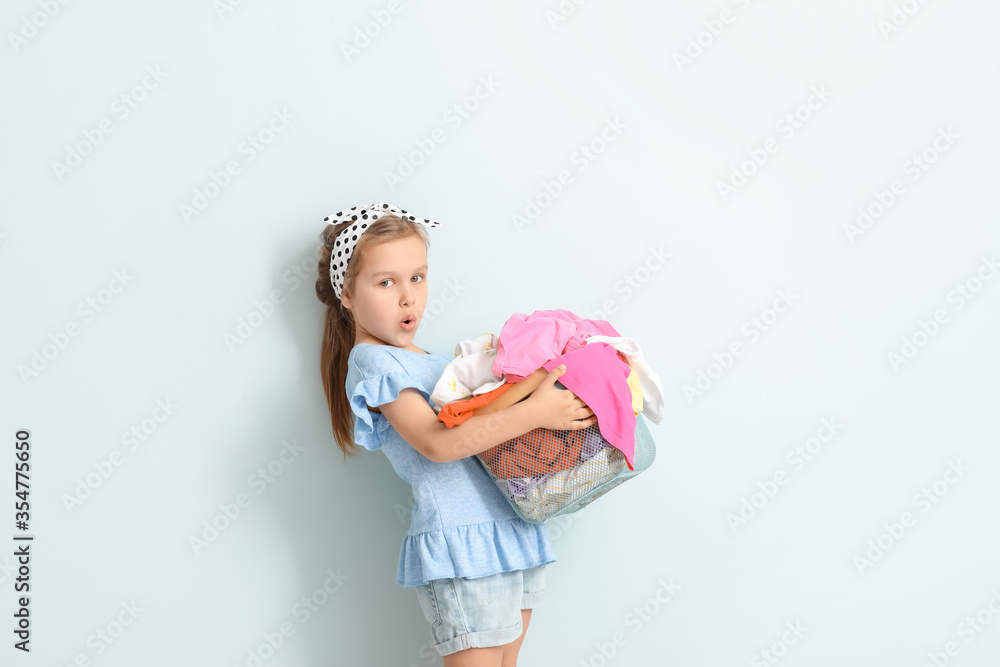 Little girl with dirty laundry on light background Little girl with dirty laundry on light background