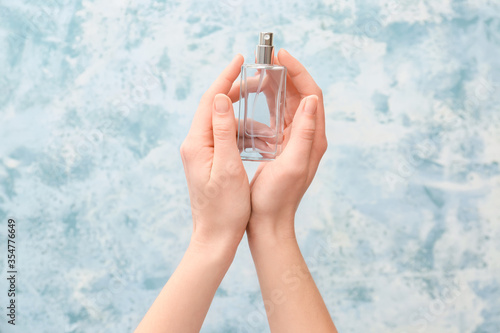 Female hands with perfume on color background