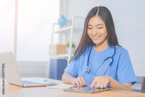 female Asian doctor working on laptop and digital tablet , writing a coronavirus positive patient a prescription hydroxychloroquine sulfate tablets.pandemic infection outbreak Coronavirus Medical photo