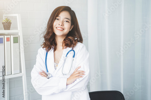 Medical health clinic beautiful Asian doctor posing smiling happy with confidence, stethoscope diagnosing patient analysis research examination healthcare provider service insurance in modern office