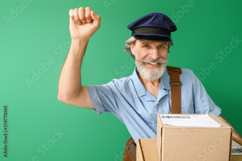 Handsome old postman on color background photo