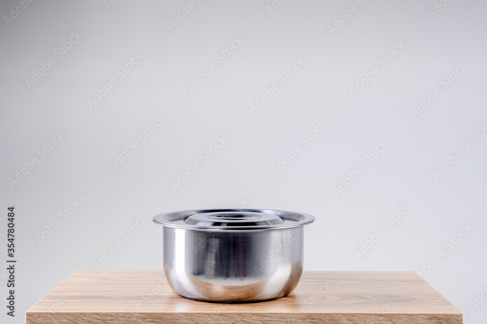 Stainless steel pot on wooden table isolated on white background. Kitchenware stainless steel. Stainless steel pot on wooden table isolated on white background. Kitchenware stainless steel.