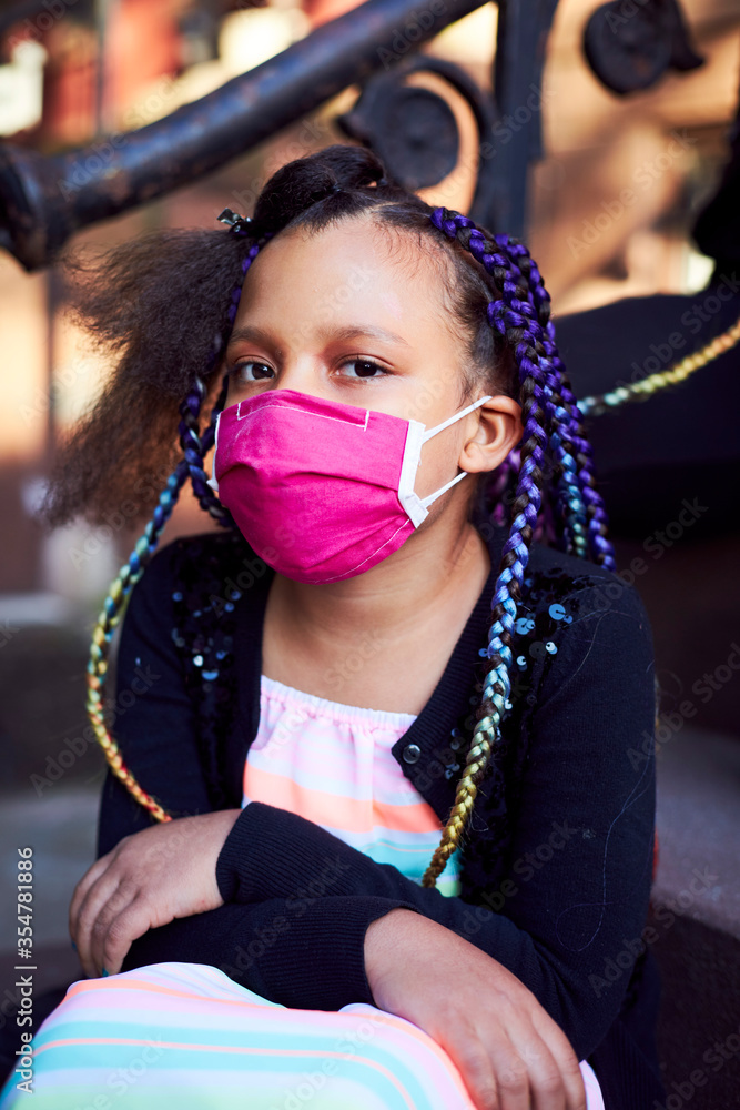 Young Mixed Race Girls Having Their Hair Braided Wearing Masks on Brownstone Stoop Stock Photo