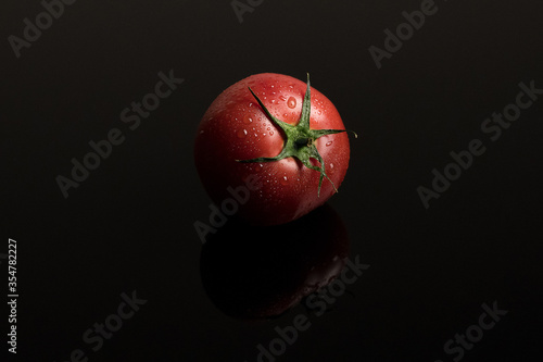 fresh wet tomato on black background with reflection