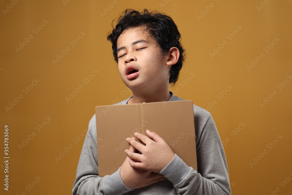Portrait of young Asian student boy tired slept and yawning when reading a book, student tired when studying hard Portrait of young Asian student boy tired slept and yawning when reading a book, student tired when studying hard