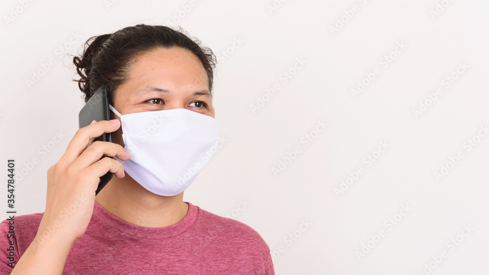 Asian man wearing white fabric mask and talking on mobile phone Asian man wearing white fabric mask and talking on mobile phone