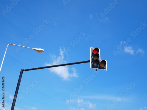 Red traffic light Universal promise to stop cars at the junction, the intersection and the street lamps on the blue sky with white clouds and sunny. Selective fogus