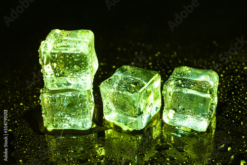 Green ice cubes on black table background.