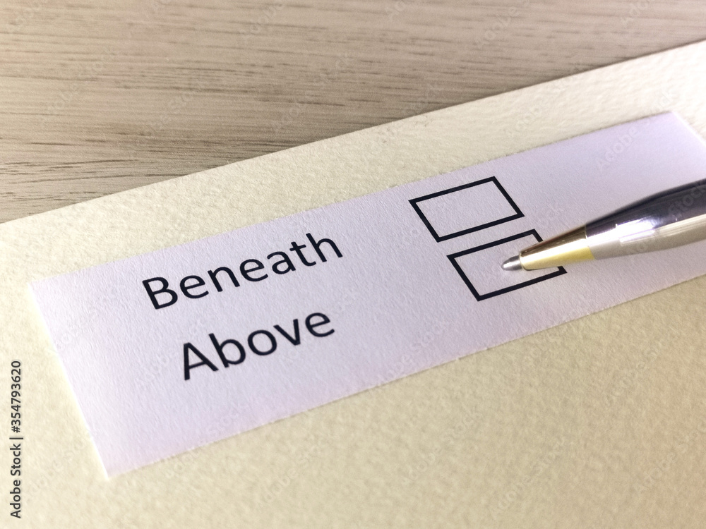 One person is answering question on a piece of paper. The person is thinking to be above or beneath. One person is answering question on a piece of paper. The person is thinking to be above or beneath.