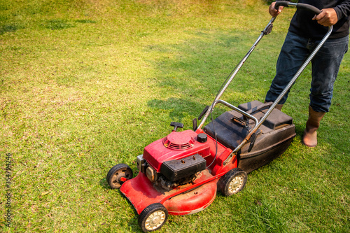 A man cutting the grass with a lawn mower