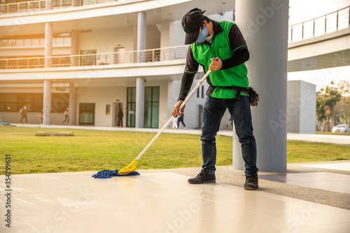 A man Janitor  wear face mask cleaning Floor With Mopping  on modern building