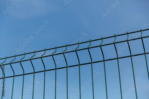 Steel grill fence with wire against the blue sky