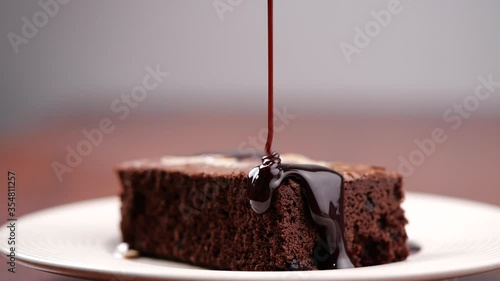Chocolate pouring on cake in slow motion. Topping chocolate on homemade brownie dessert photo