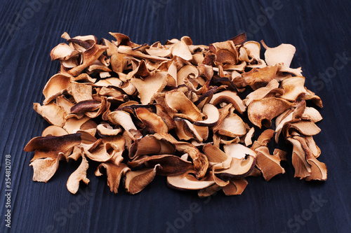 Edible dried mushrooms pile black wooden background close up, dry boletus edulis heap dark wood backdrop, chopped brown cap boletus, sliced penny bun, cep pieces, porcino, porcini, cutted white fungus