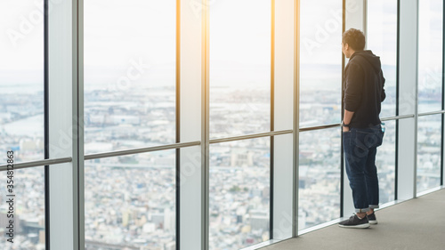 Canvas Print young Asian man standing and  looking out window glass on top of Umeda Sky Building at osaka Japan