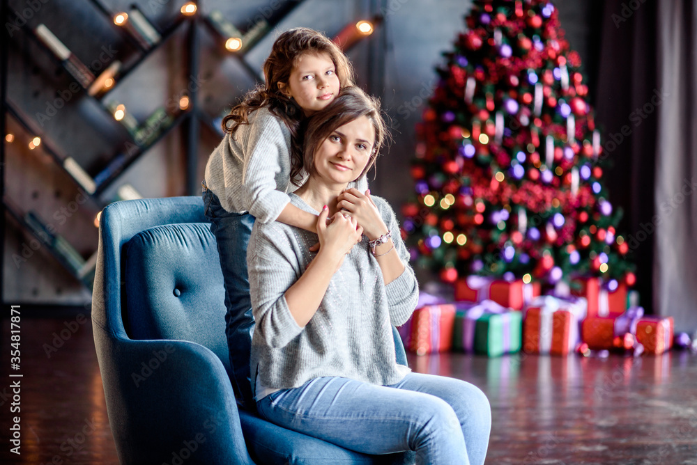 Naklejka premium Mother and Child Hug in Front of a Christmas Tree.
