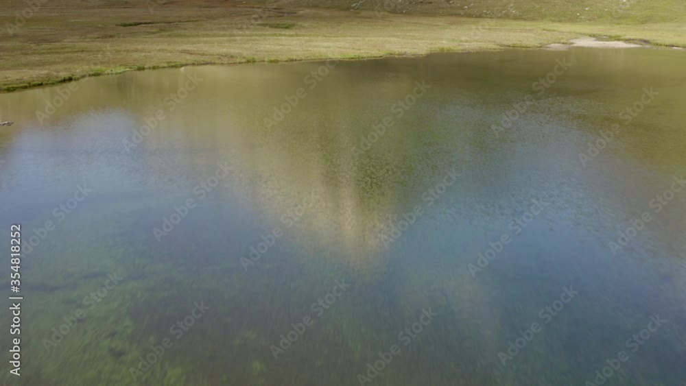 Aerial tilt up shot of river flowing against mountain on sunny day, drone flying forward over natural landscape against sky - Swiss Alps, Switzerland Aerial tilt up shot of river flowing against mountain on sunny day, drone flying forward over natural landscape against sky - Swiss Alps, Switzerland