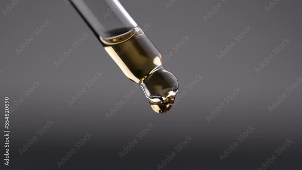 Essential oil dropping from glass dropper in slow motion