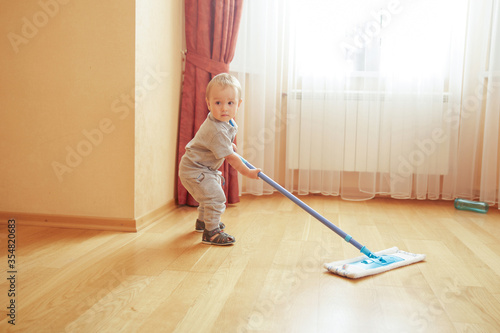 Adorable baby boy helping cleaning room floor