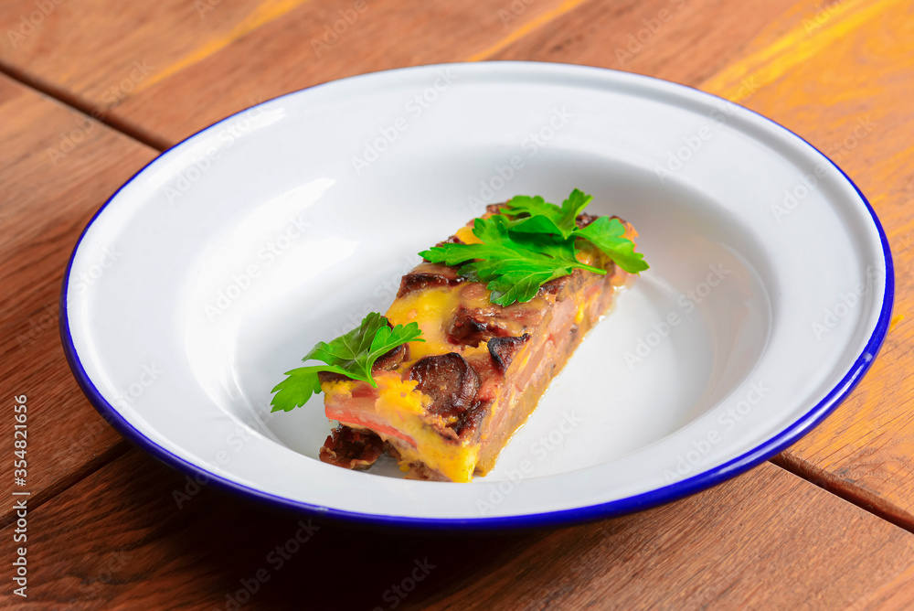 Homemade meat casserole with mushrooms and tomatoes and fresh pardley served on white plate over wooden background. Homemade meat casserole with mushrooms and tomatoes and fresh pardley served on white plate over wooden background.