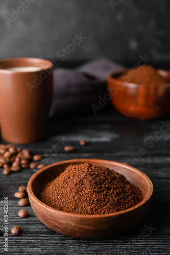 Bowl with coffee powder and beans on table