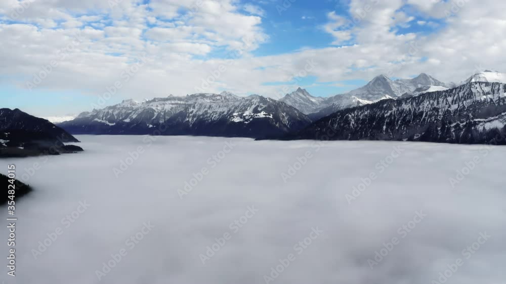 A sea of clouds above the valley and the snowy mountains in the background. Over Lake Thun and the mountain Schreckhorn, Mittelhorn, Eiger and Mönch. A sea of clouds above the valley and the snowy mountains in the background. Over Lake Thun and the mountain Schreckhorn, Mittelhorn, Eiger and Mönch.