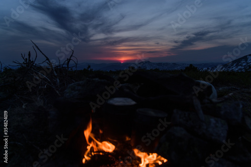 Sunset against mountains  in the foreground a bonfire warms up water