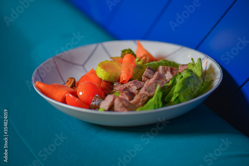 Roasted meat and vegetables salad with tomatoes and brocolli served in a white bowl. Healthy dinner.