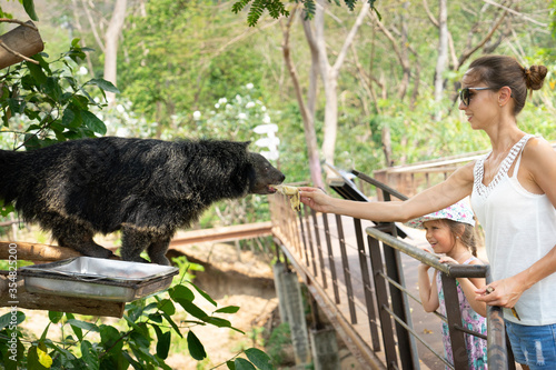 Tourists at the zoo in Thailand feed Binturong. © victor21041958