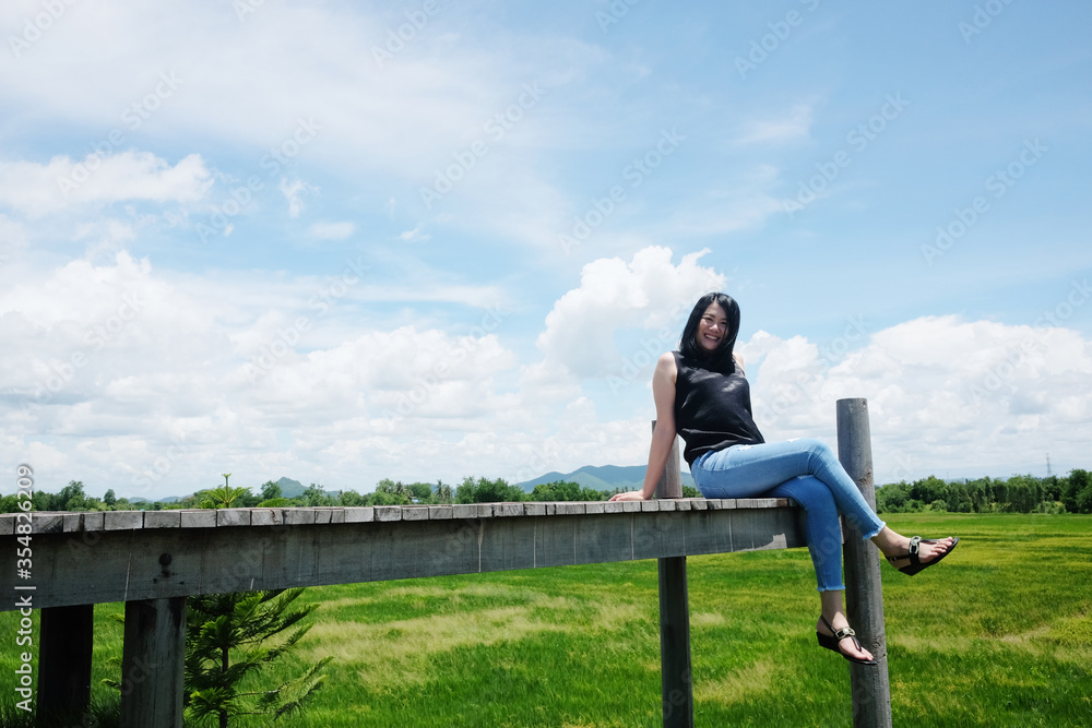 Asian woman sitting on Wooden bridge is freedom and happy on the blue sky. Happiness of life is successful and travel in the world.