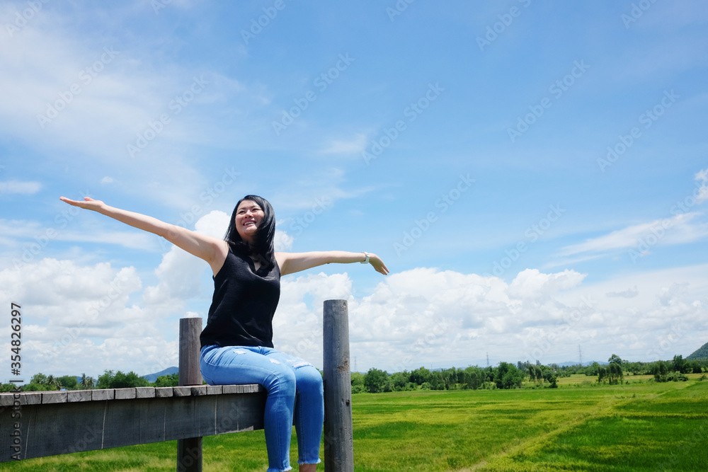 Asian woman sitting on Wooden bridge and open arms for freedom and happy on the blue sky. Happiness of life is successful and travel in the world. Asian woman sitting on Wooden bridge and open arms for freedom and happy on the blue sky. Happiness of life is successful and travel in the world.