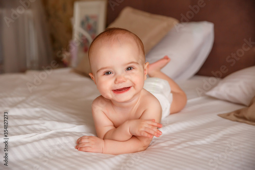 baby in a diaper
 lying on the bed at home smiling