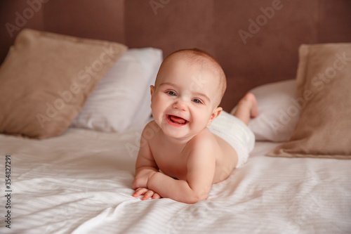 baby in a diaper lying on the bed at home smiling