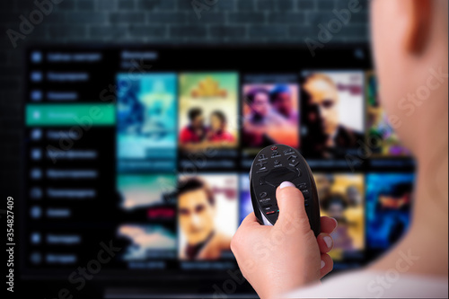 Multimedia streaming concept. woman holds remote control. TV screen with lot of pictures.