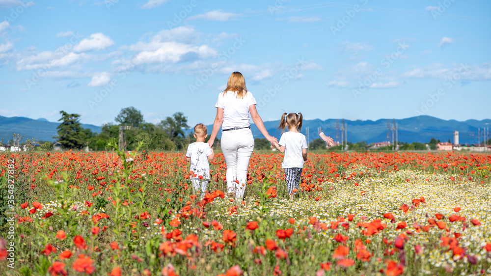 Mother with daughter and son on a field with poppies on a sunny day Mother with daughter and son on a field with poppies on a sunny day