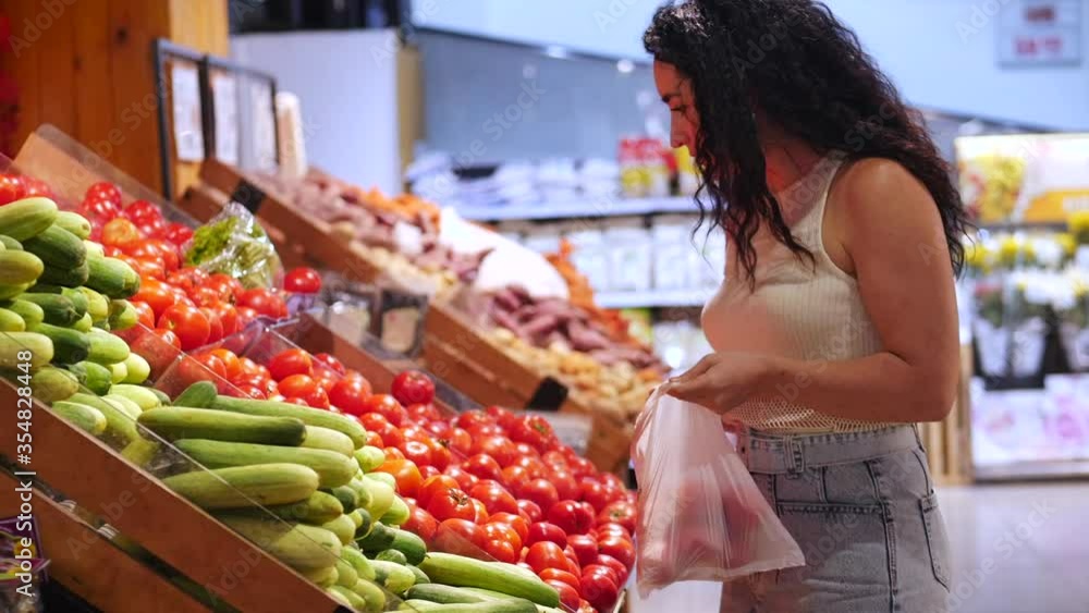 Pretty young woman or mom is making purchases in the supermarket, choosing products at the supermarket for cooking, healthy foods, tomatoes, avocados, fruits, oranges at the market, supermarket. Pretty young woman or mom is making purchases in the supermarket, choosing products at the supermarket for cooking, healthy foods, tomatoes, avocados, fruits, oranges at the market, supermarket.